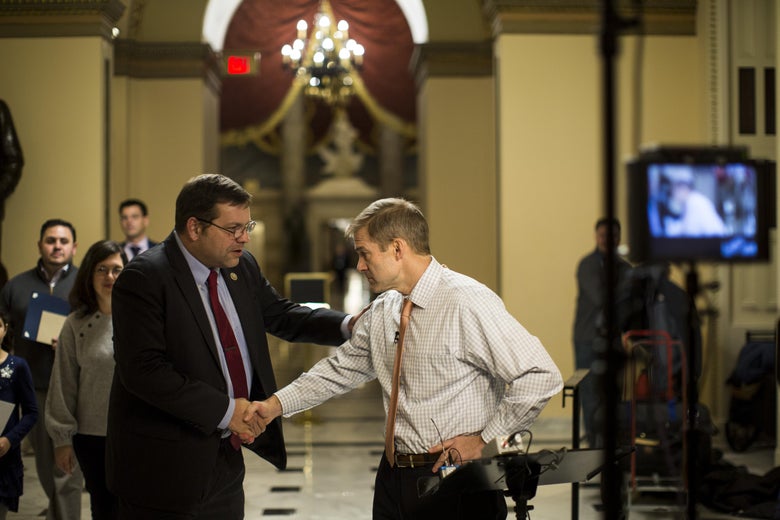 Tom Garrett grabs the shoulder of and shakes hands with Jim Jordan.